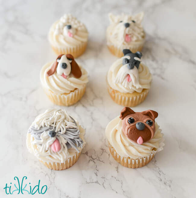 Cupcakes with edible gum paste dog cupcake toppers on a white marble background
