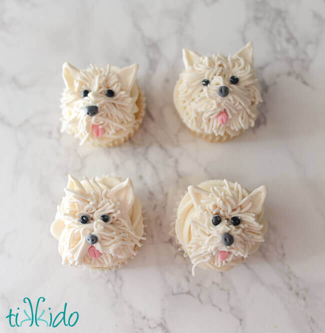 Four cupcakes decorated with gum paste Westie terriers