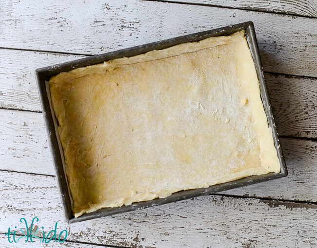 9x13 pan lined with unbaked pie crust on a weathered white wooden background
