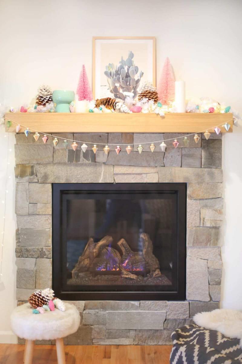 Christmas garland made with christmas ornaments, hanging from a stone fireplace.