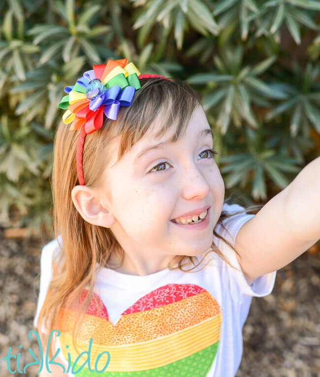 Little girl wearing a DIY Rainbow ribbon flower headband.