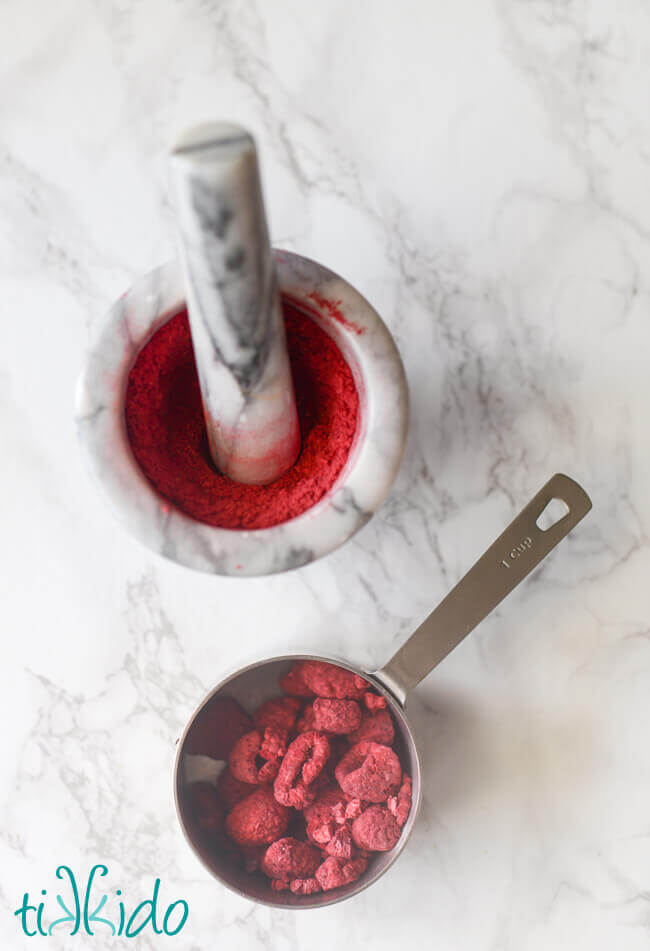 Freeze dried raspberries in a cup measure and freeze dried raspberries ground to a powder in a marble mortar and pestle