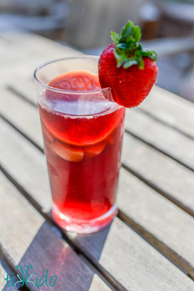 Glass of red sangria garnished with a strawberry.