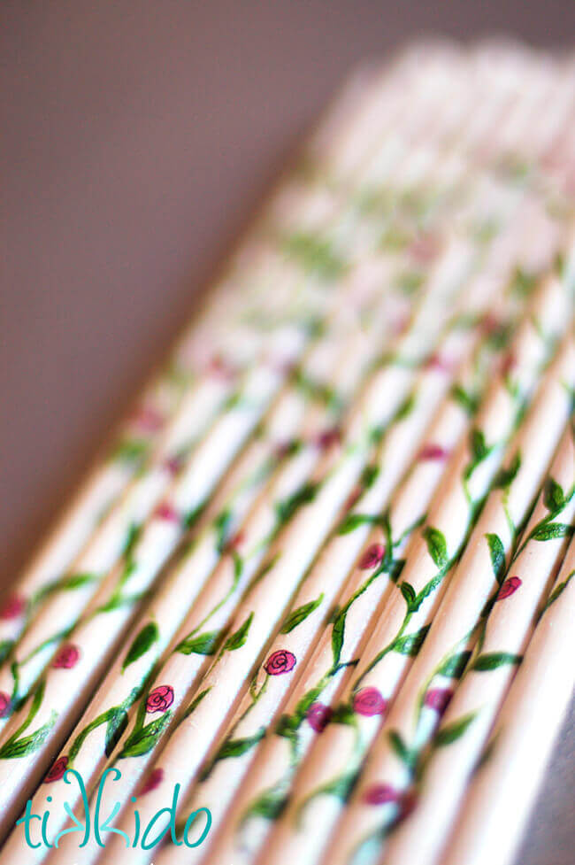 Wooden dowels painted white, and with a climbing rose motif to serve as the wands for DIY ribbon wands.