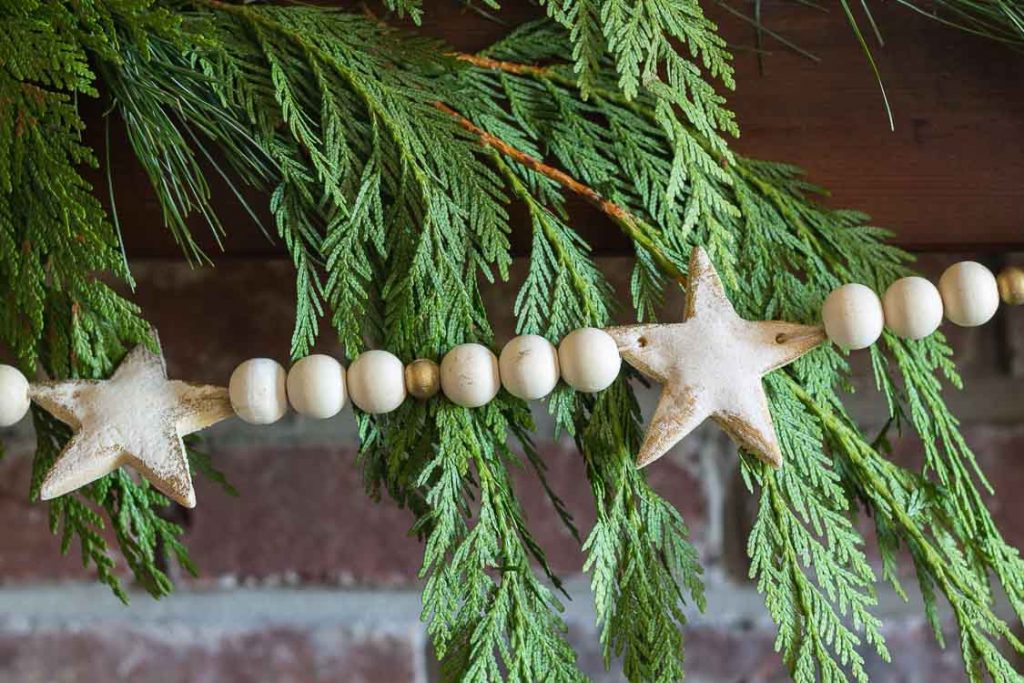 Salt dough star Christmas garland hanging in front of fresh evergreen branches.