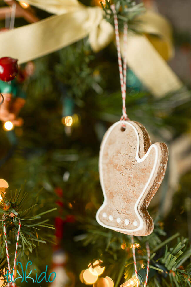 Salt dough ornament that looks like a gingerbread cookie hanging on a Christmas tree.