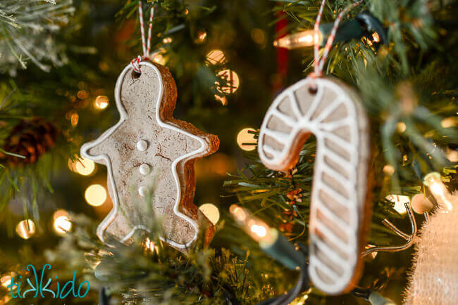 Salt dough ornaments that look like  gingerbread cookies hanging on a Christmas tree.
