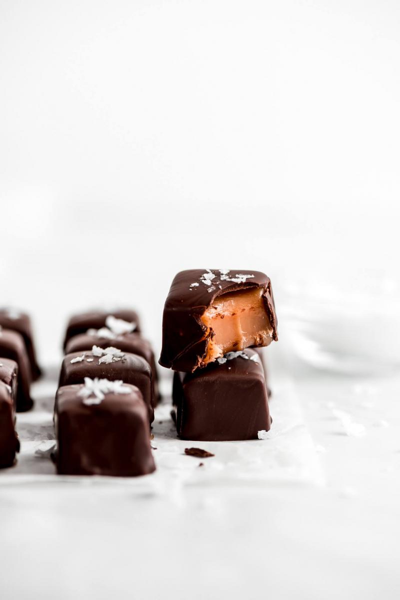 Chocolate covered caramels topped with sea salt on a white background.