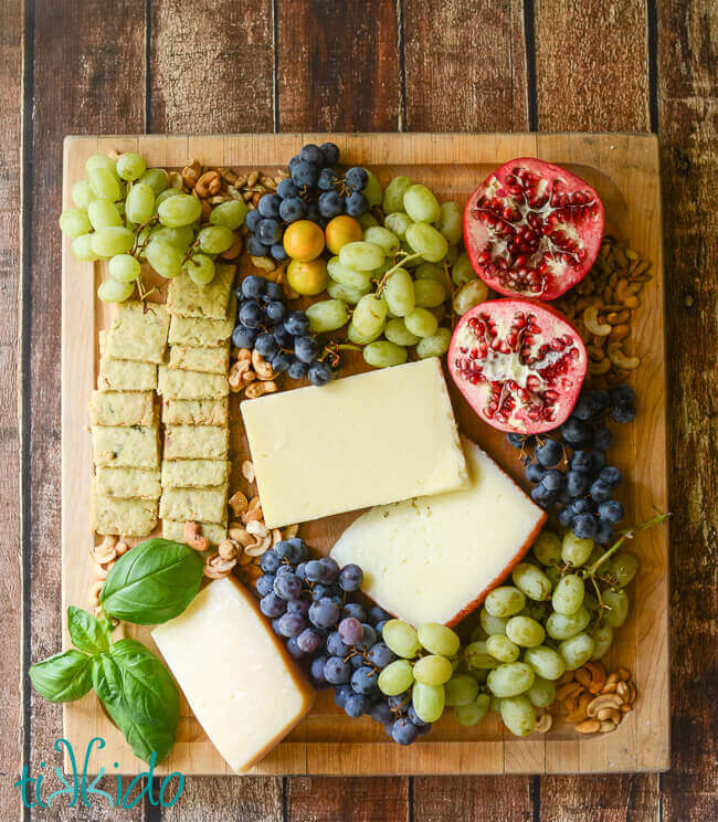 Cheese, fruit, and savory shortbread crackers on a cutting board.