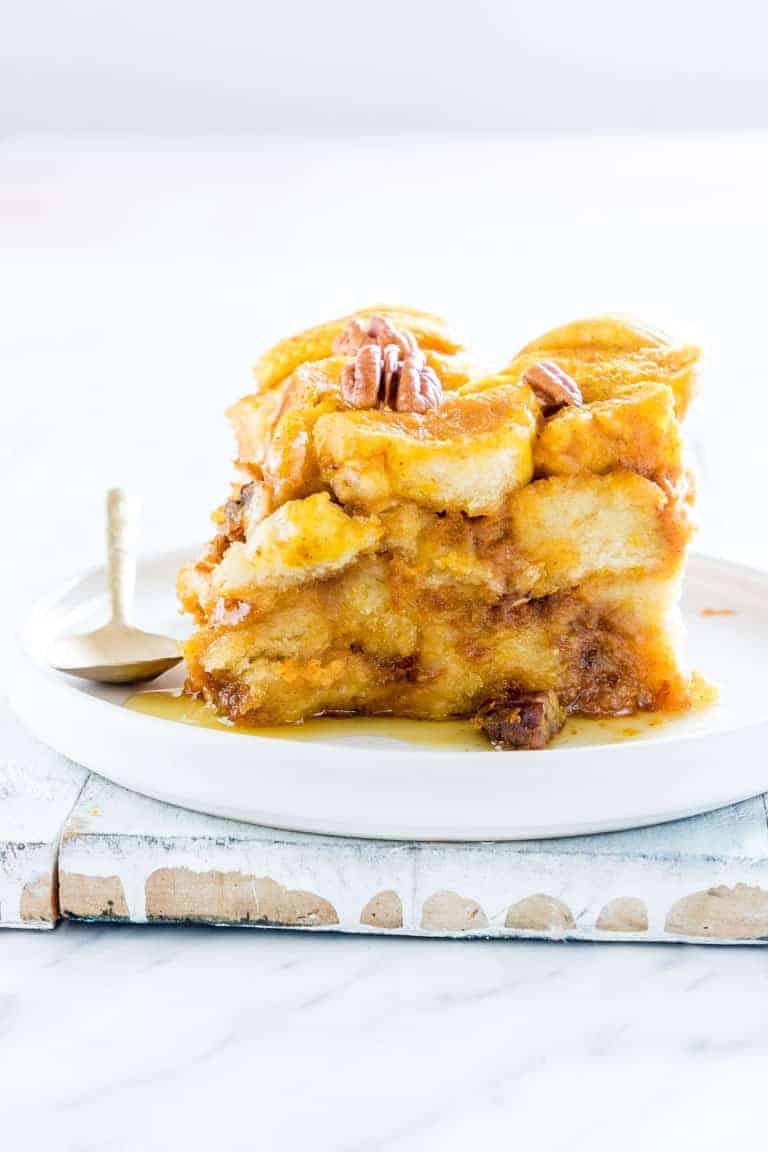 Crockpot pumpkin bread pudding served on a white plate, and topped with pecans.