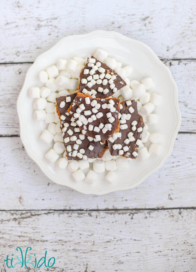 S'mores Graham Cracker Toffee on a white plate covered in mini marshmallows.
