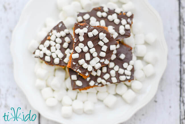 Plate of pieces of S'mores Toffee on a white plate covered in mini marshmallows.