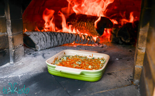 Light spinach artichoke dip being baked in a wood fired pizza oven.
