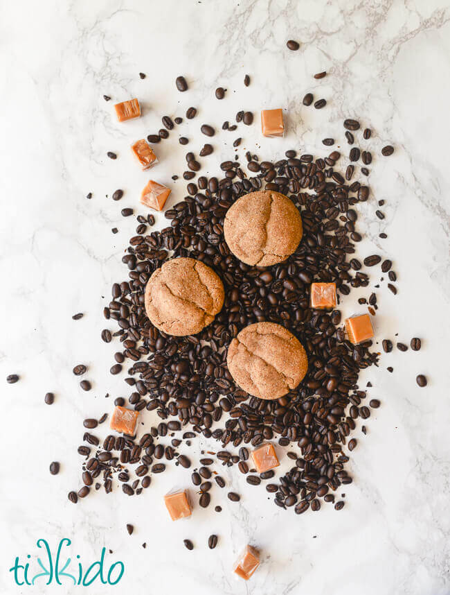 Coffee flavored cookies stuffed with caramel on a bed of coffee beans and caramel candies.