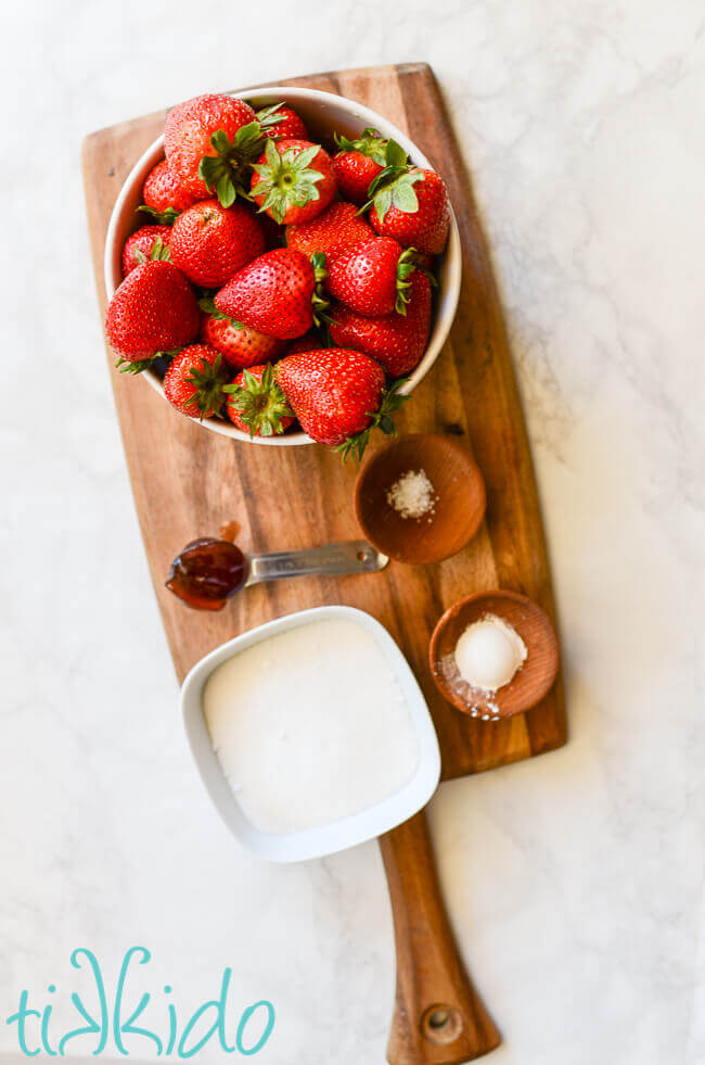 Ingredients for homemade strawberries on a wooden cutting board.