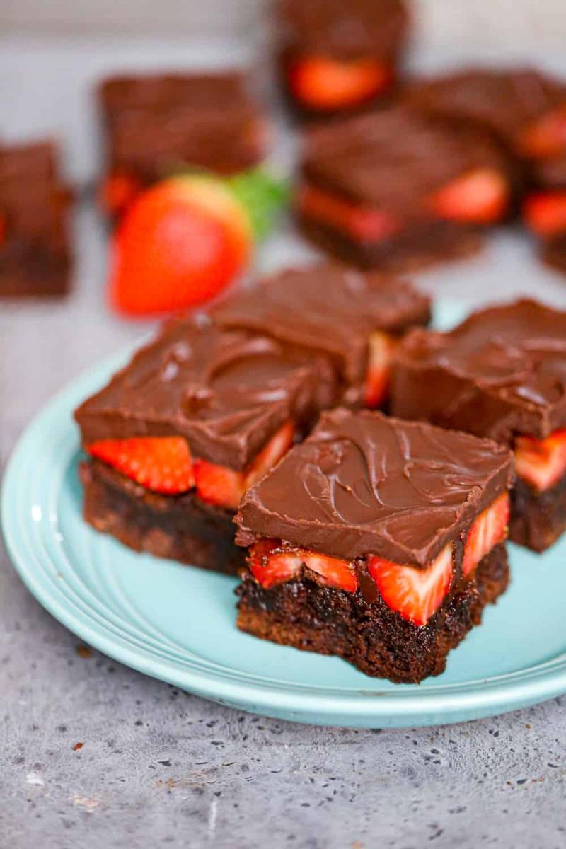 Blue plate with four slices of chocolate covered strawberry brownies.