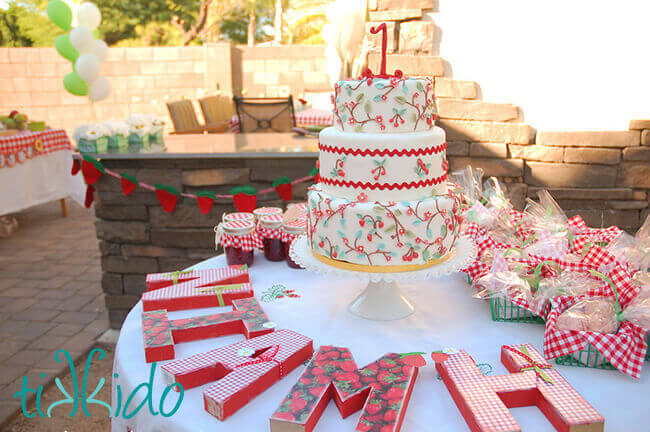 Calico red and white cake on a round table at the Strawberry Picnic birthday party.