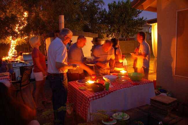 People moving around a wood fired pizza oven at night.