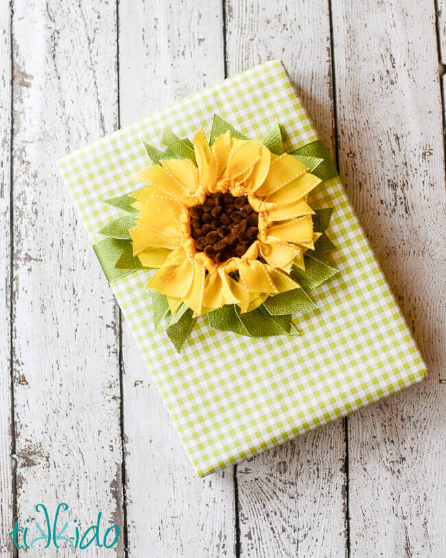 DIY ribbon sunflower gift topper on a green gingham check wrapped gift.