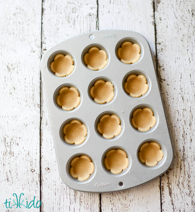 Sugar cookie dough cut into flower shapes and pressed into a mini muffin tin.