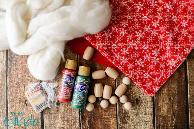 Wooden beads, paint, red fabric, and wool roving for making Scandinavian tomte ornaments.