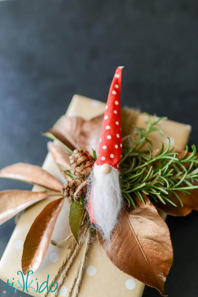 Scandinavian tomte Christmas elf ornament used as a gift topper.