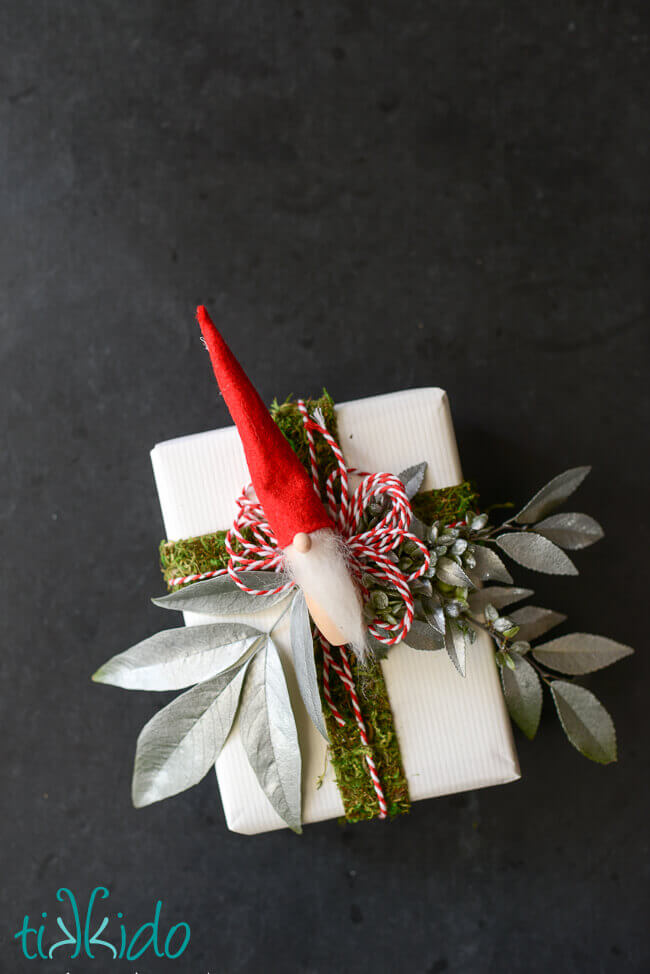 Scandinavian tomte Christmas elf ornament used as a gift topper.