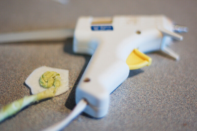 Twisted fabric flower being made by gluing a strip of twisted fabric in a coil on a circle of felt.