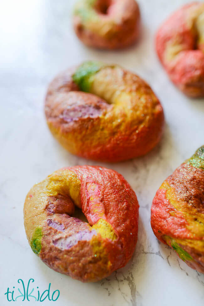 Rainbow Unicorn bagels on a white marble background.