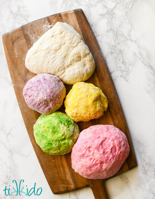 Bagel dough divided into five parts and colored purple, yellow, green, and pink for unicorn bagels.