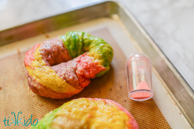 Rainbow Unicorn bagels being sprinkled with disco dust edible glitter before baking.