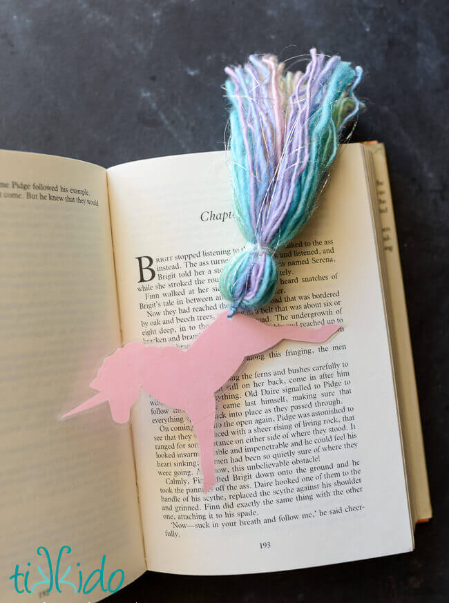 Unicorn bookmark resting on the pages of an open book.