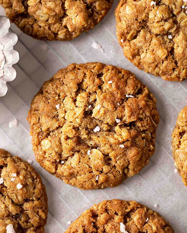 Chewy vegan oatmeal cookies sprinkled with sea salt on parchment paper.