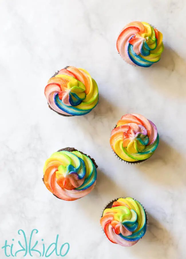 Chocolate cupcakes topped with a rainbow swirl of American buttercream frosting.