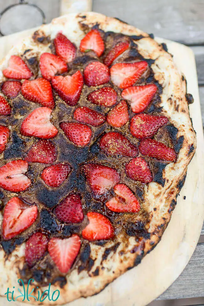 Chocolate covered strawberry dessert pizza on a wooden pizza peel.