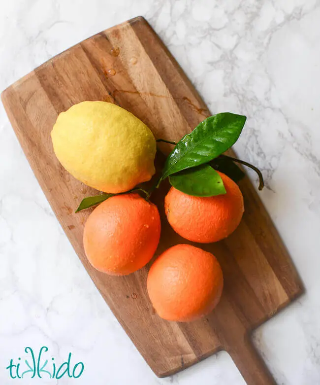 Freshly picked oranges and lemons on a wooden cutting board.