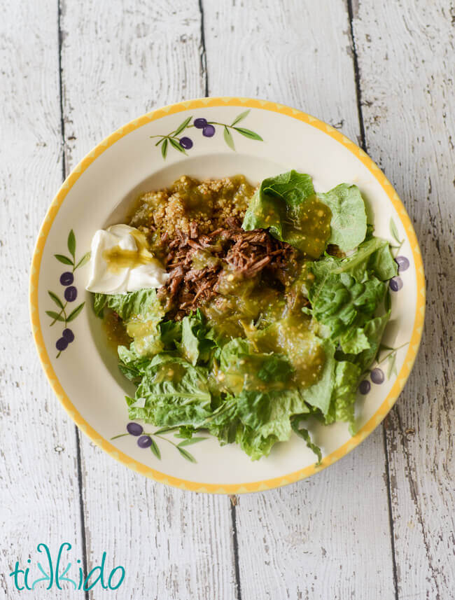 Quinoa and mexican shredded beef burrito bowl on a white weathered wood background