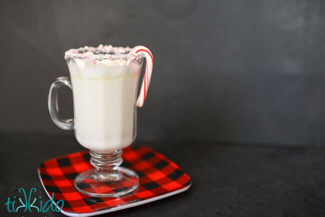 White hot chocolate in a clear mug on a black background.