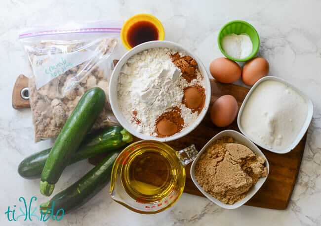 Zucchini bread ingredients on a wooden cutting board.