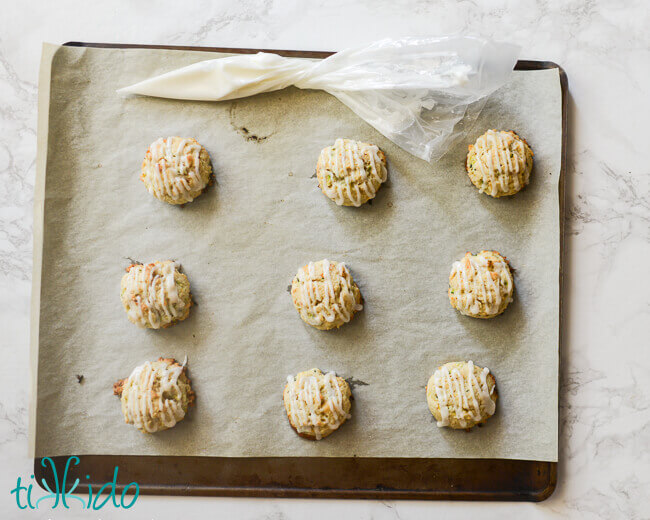 Baked soft zucchini cookies being drizzled with lemon glaze.